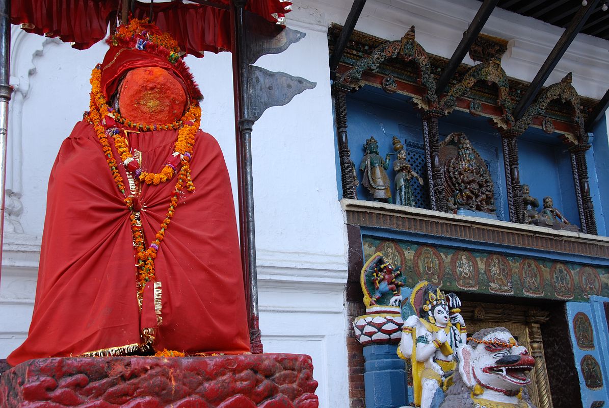 Kathmandu Durbar Square 06 03 Hanuman Statue And Entrance Gate Stone lions flank the sides of the Hanuman Dhoka gate in Kathmandu�s Durbar Square, one ridden by Shiva, the other by his wife Parvati. Above the gate a brightly painted niche is illustrated with a central figure of a ferocious Tantric version of Krishna. On the left side is the gentler Hindu Krishna in his traditional blue colour accompanied by two of his comely milkmaids. On the right side are King Pratap Malla and his queen.